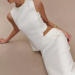 Elegant white asymmetric sleeveless top with pearl button detail, styled with matching trousers and gold jewelry — Endless | Endless UAE