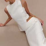 Elegant white asymmetric sleeveless top with pearl button detail, styled with matching trousers and gold jewelry — Endless | Endless UAE