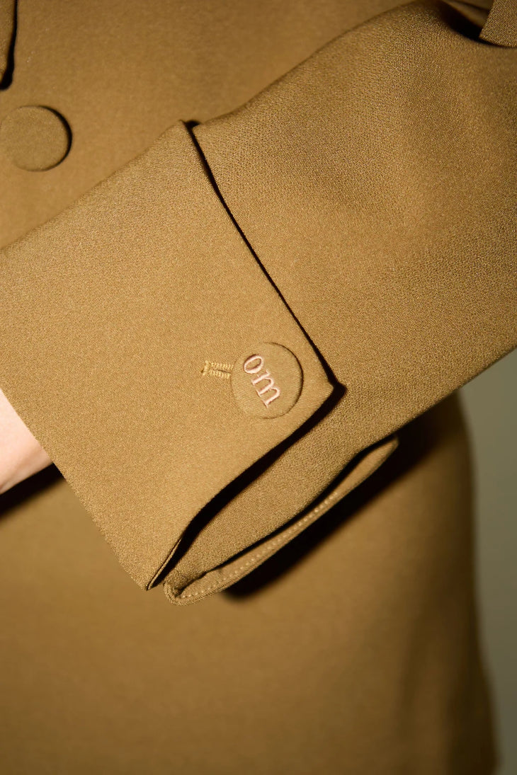 Olive green blazer jacket detail showing circular logo button and tailored sleeve cuff — Odd Muse | Endless UAE