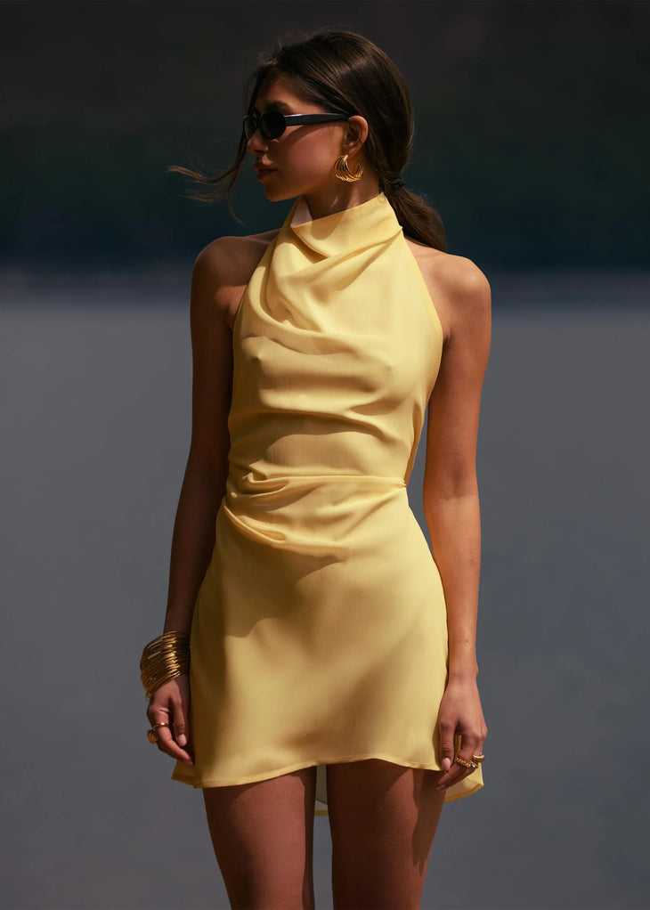 Woman wearing yellow halter neck dress on beach with sunglasses and accessories — Dvete | Endless UAE