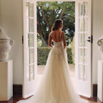 Bride in ivory tulle ballgown with floral embroidered bodice and illusion back standing in elegant doorway — You&I Bridal | Endless UAE