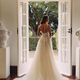 Bride in ivory tulle ballgown with floral embroidered bodice and illusion back standing in elegant doorway — You&I Bridal | Endless UAE