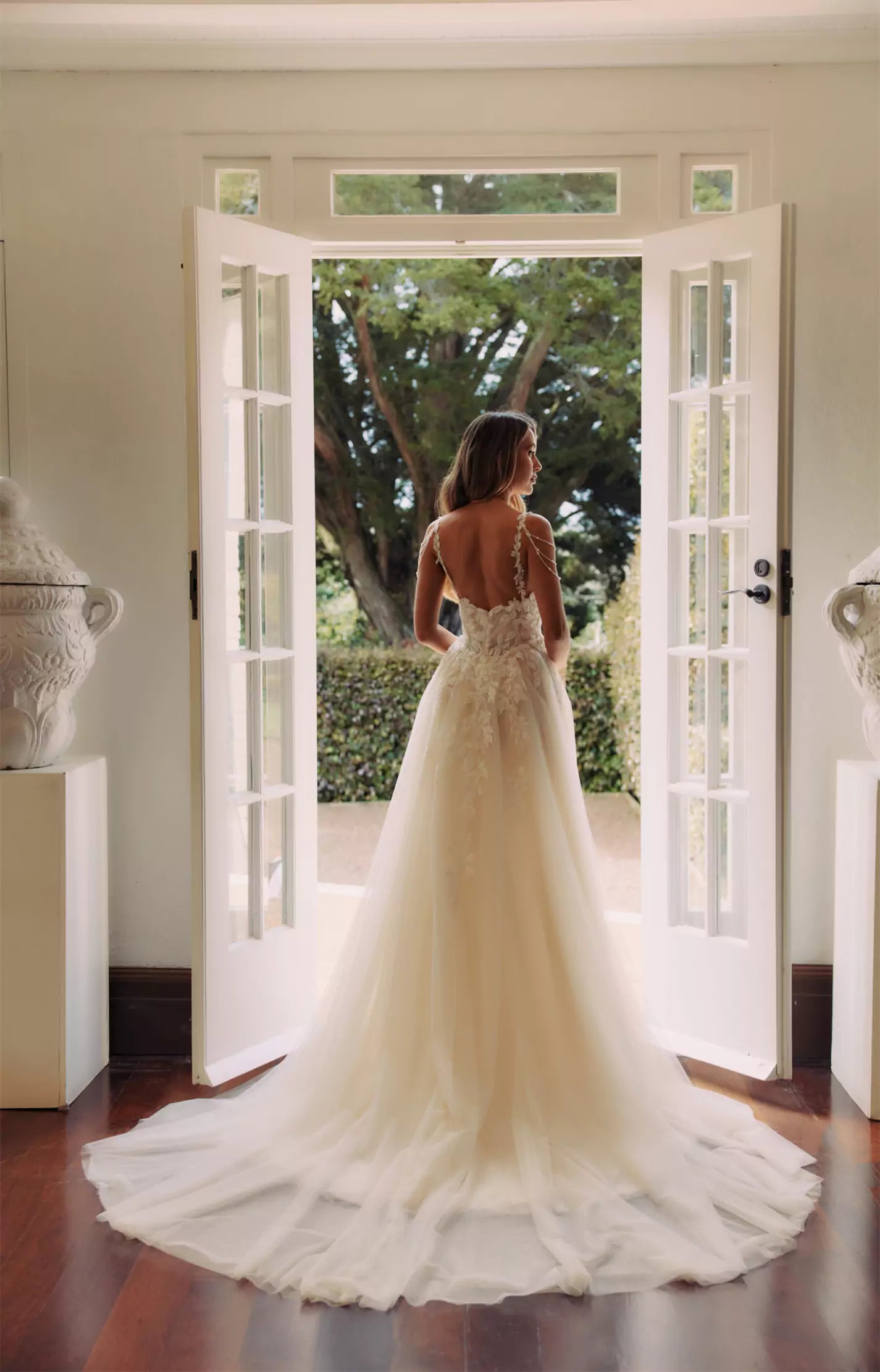Bride in ivory tulle ballgown with floral embroidered bodice and illusion back standing in elegant doorway — You&I Bridal | Endless UAE