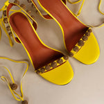 Bright yellow Bellaria heels with glittery gold embellishments and ankle-tie straps on beige background — Subashini Heels | Endless UAE