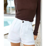 White linen high-waisted shorts with cuffed hem and button closure paired with brown ribbed top — Sandys | Endless UAE