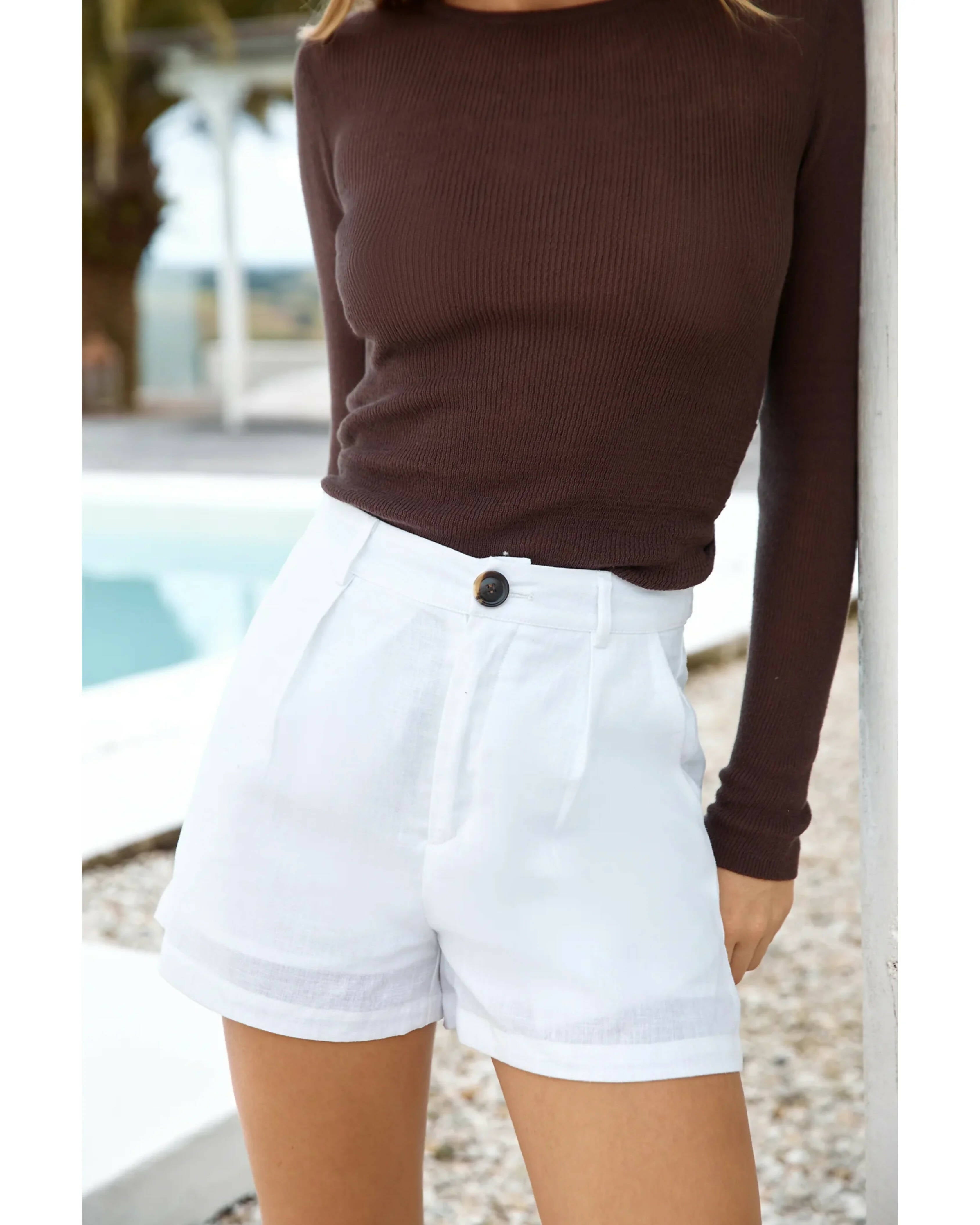 White linen high-waisted shorts with cuffed hem and button closure paired with brown ribbed top — Sandys | Endless UAE