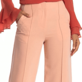 Woman wearing blush pink high-waisted wide leg trousers with a coral red blouse on white background — Diane Von Furstenberg | Endless UAE
