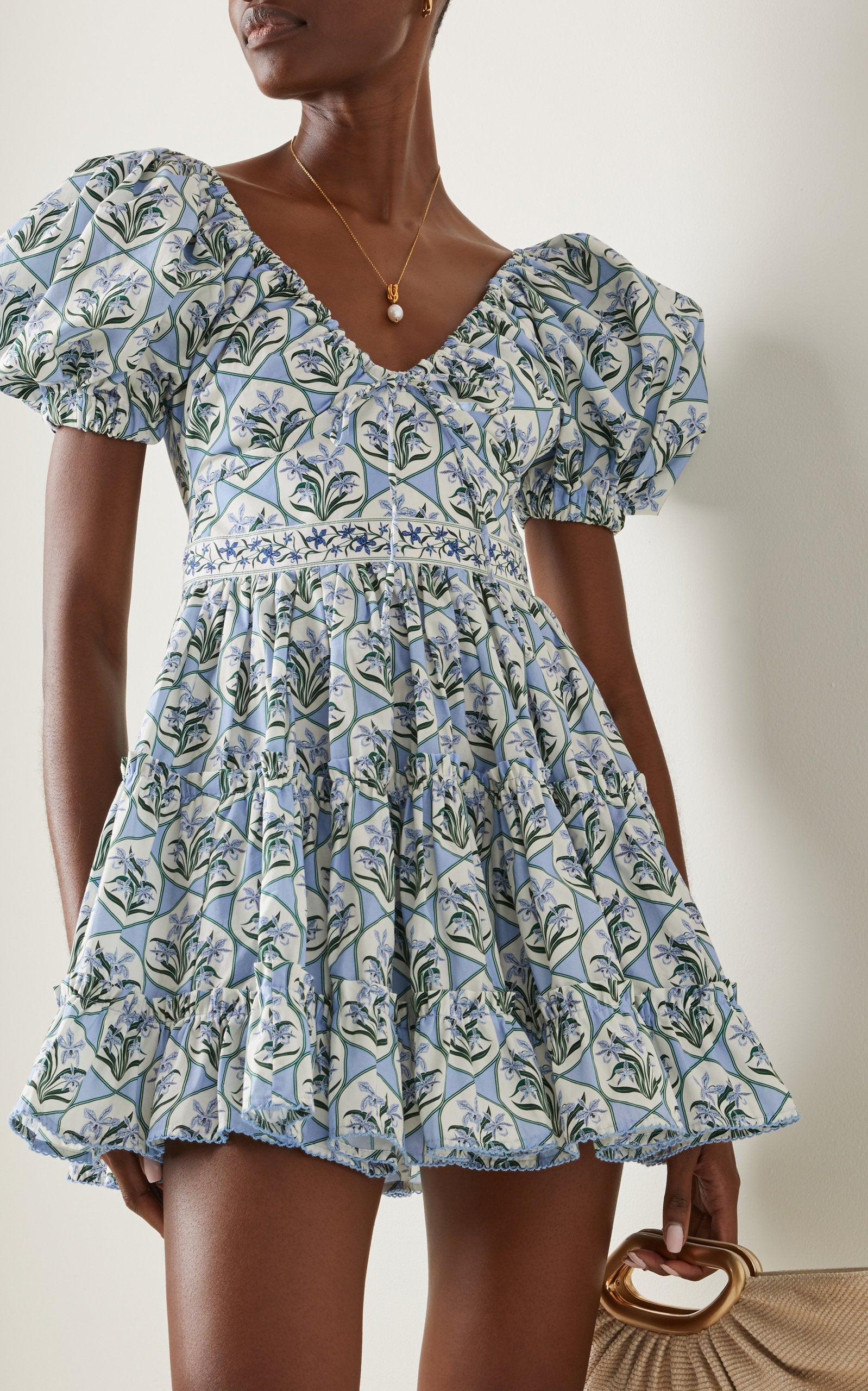 Woman wearing blue floral cotton mini dress with puff sleeves and cream tote bag — Agua by Agua Bendita | Endless UAE