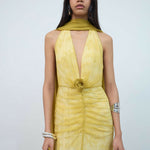 Woman wearing yellow halter maxi dress with deep V-neckline and circular buckle detail — Endless | Endless UAE