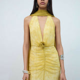 Woman wearing yellow halter maxi dress with deep V-neckline and circular buckle detail — Endless | Endless UAE
