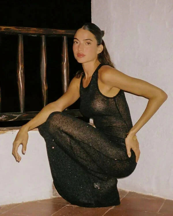 Sleeveless black sparkle knit midi dress with sheer texture worn in crouched pose — Asta Resort | Endless UAE