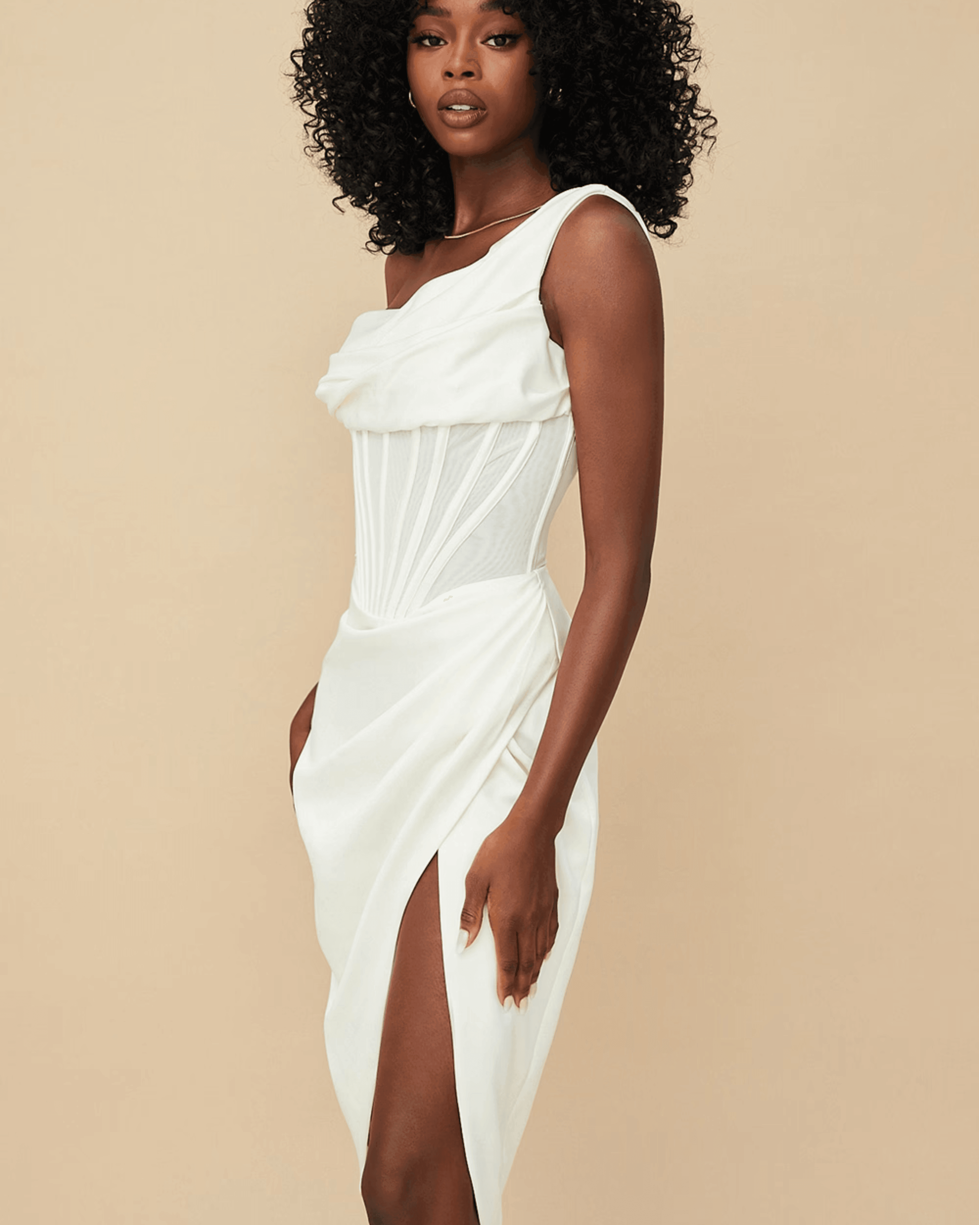 Elegant white asymmetric corset midi dress with sheer mesh panel, draped bodice and high slit modeled on beige background — House of CB | Endless UAE