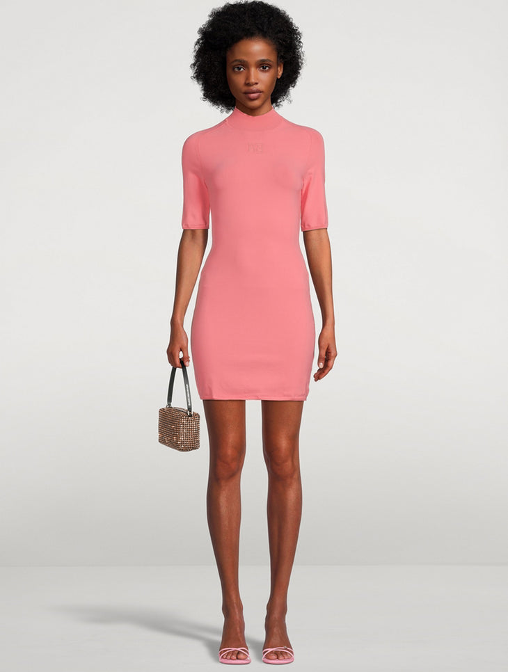 Woman wearing coral pink short-sleeve bodycon mini dress with mock neck, holding beaded handbag and pink sandals — Alexander Wang | Endless UAE