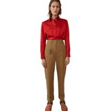 Woman wearing tan Madya Co chinos with cuffed hems and red polo shirt, styled with leather sandals — Acne Studios | Endless UAE