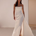 Elegant white strapless bridal gown with draped bodice and high slit, paired with strappy sandals — Milla Nova | Endless UAE