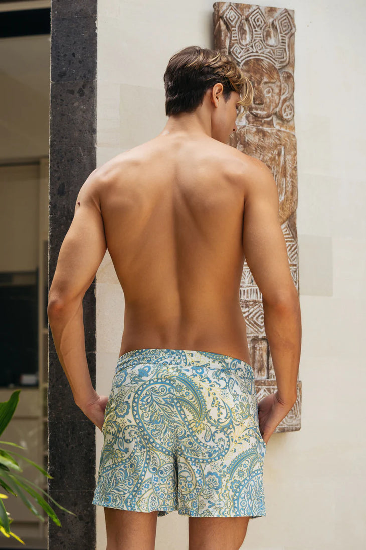 Shirtless man wearing blue and cream paisley patterned swim trunks viewed from behind — Miharo | Endless UAE
