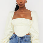 Cream off-shoulder corset top with dramatic balloon sleeves paired with blue jeans — House of CB | Endless UAE