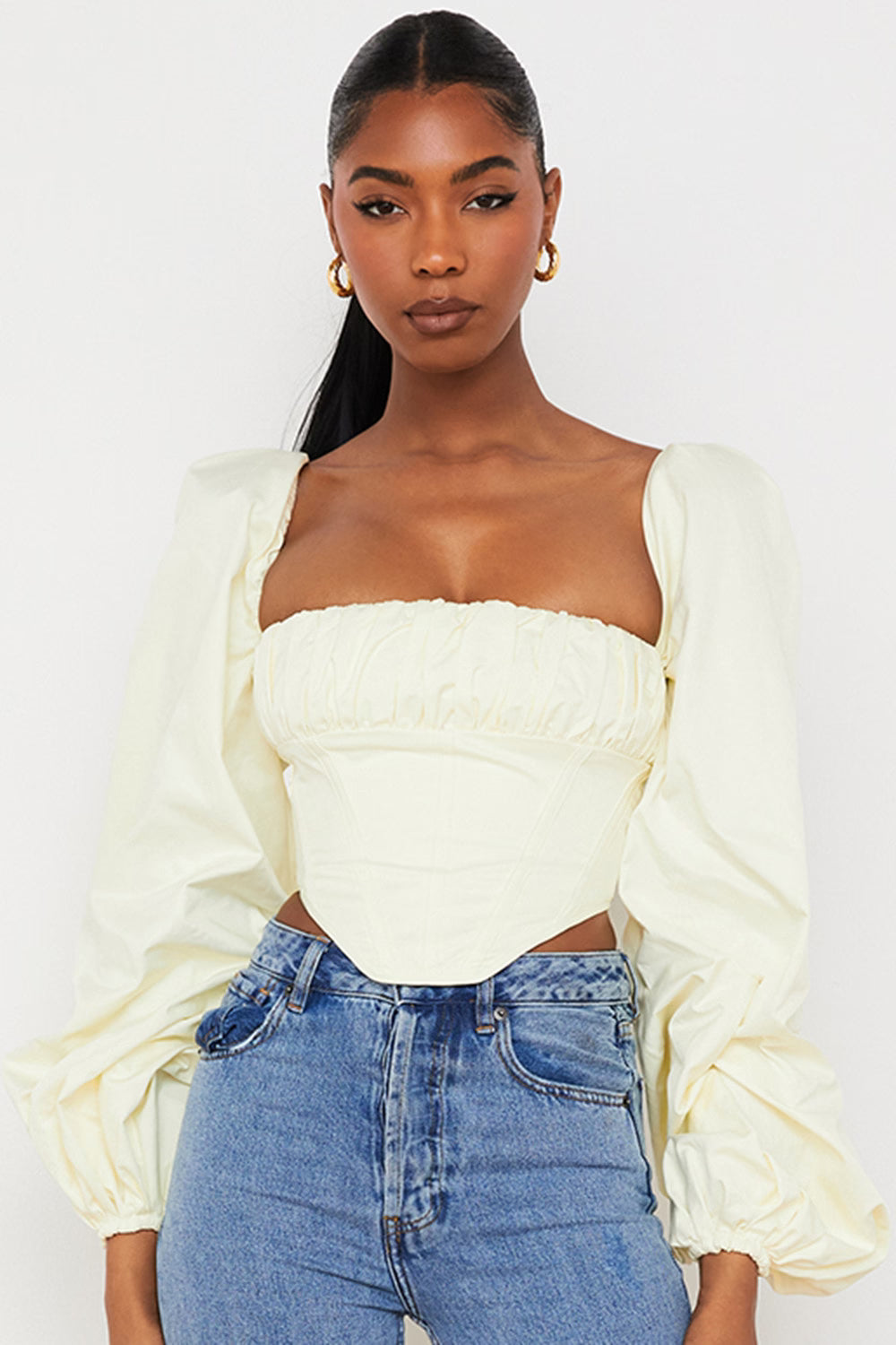 Cream off-shoulder corset top with dramatic balloon sleeves paired with blue jeans — House of CB | Endless UAE