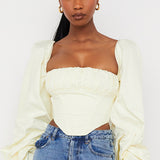 Cream off-shoulder corset top with dramatic balloon sleeves paired with blue jeans — House of CB | Endless UAE