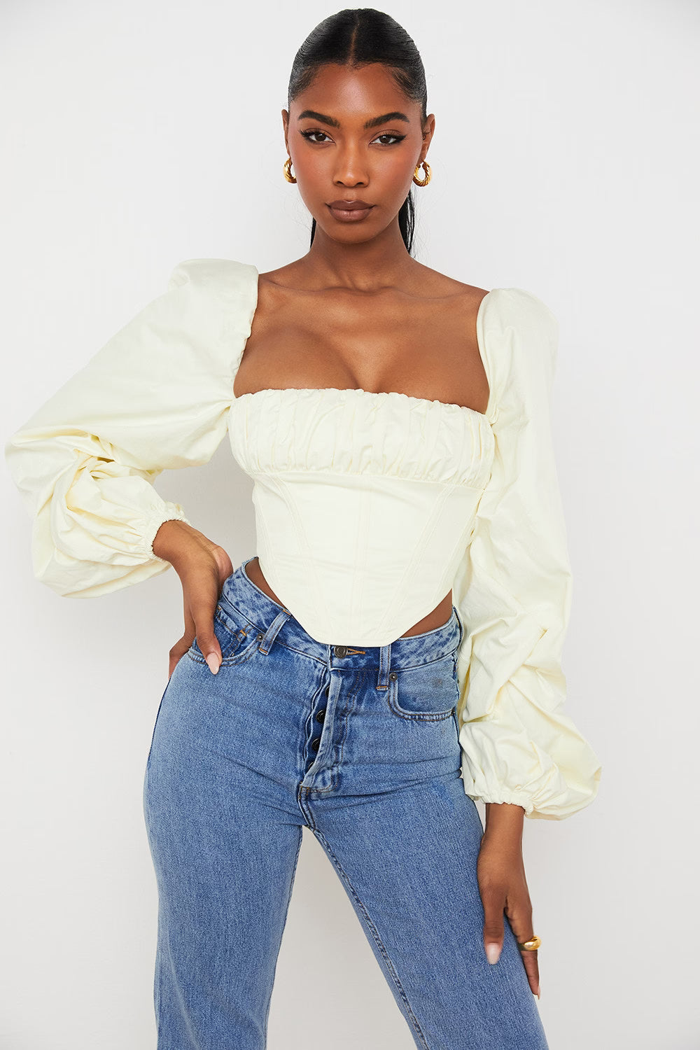 Cream off-shoulder corset top with dramatic balloon sleeves paired with blue jeans — House of CB | Endless UAE