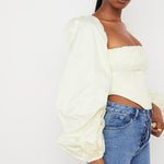 Pale yellow corset top with dramatic puff sleeves and square neckline paired with blue jeans — House of CB | Endless UAE