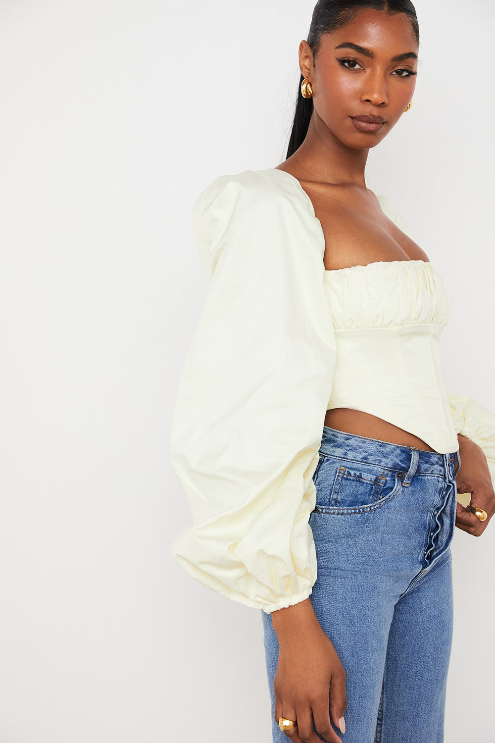 Pale yellow corset top with dramatic puff sleeves and square neckline paired with blue jeans — House of CB | Endless UAE