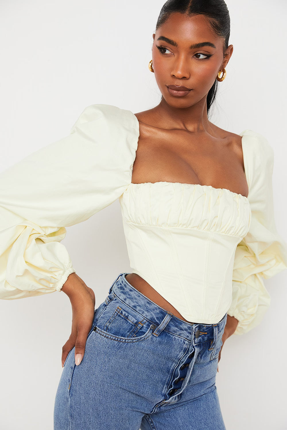 Elegant cream corset top with dramatic puffed balloon sleeves and straight neckline paired with denim jeans — House of CB | Endless UAE