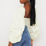 Woman wearing cream balloon sleeve corset top with blue jeans viewed from side — House of CB | Endless UAE
