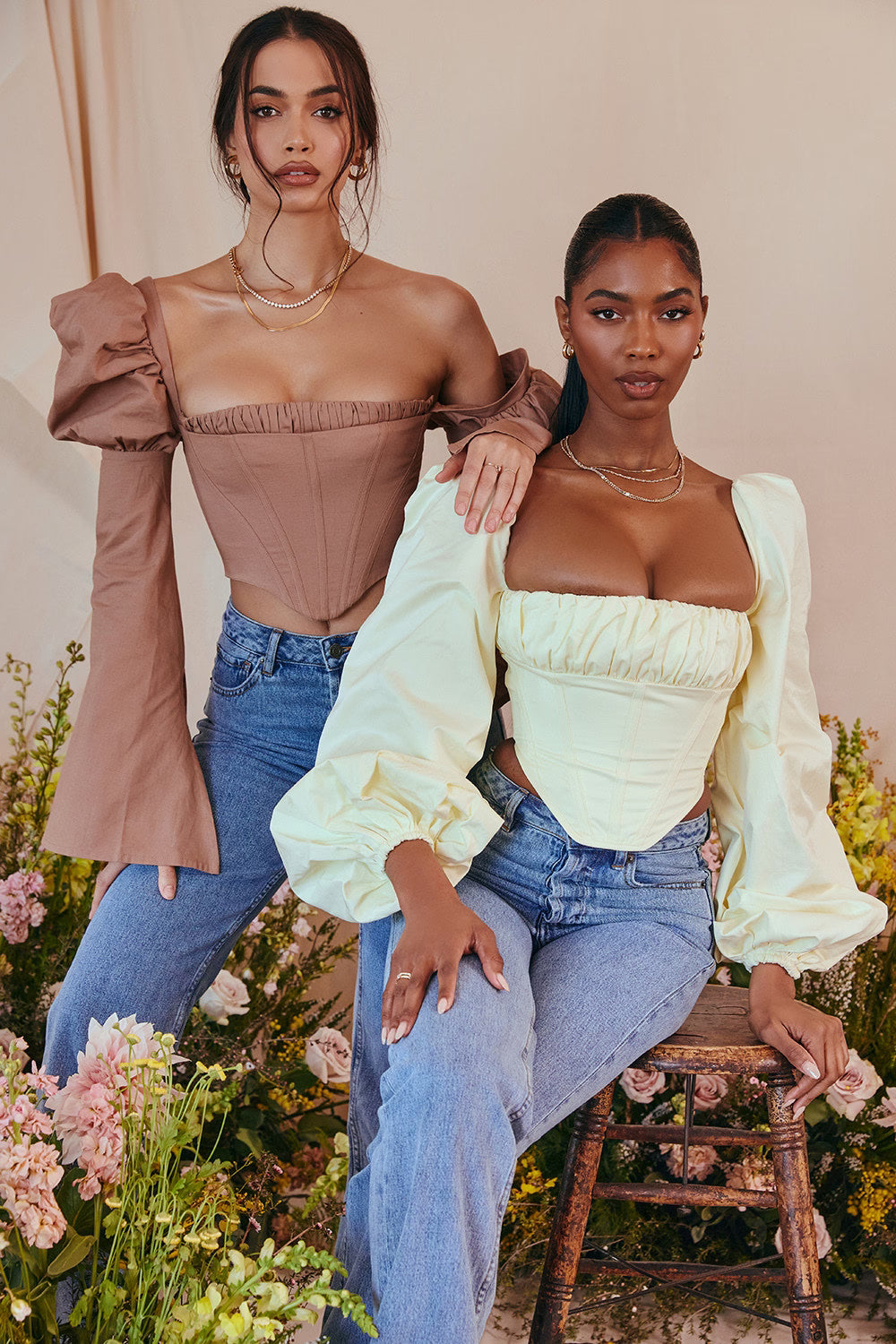 Miriam Balloon Sleeve Corset in taupe and yellow worn with jeans by two models in floral setting — House of CB | Endless UAE