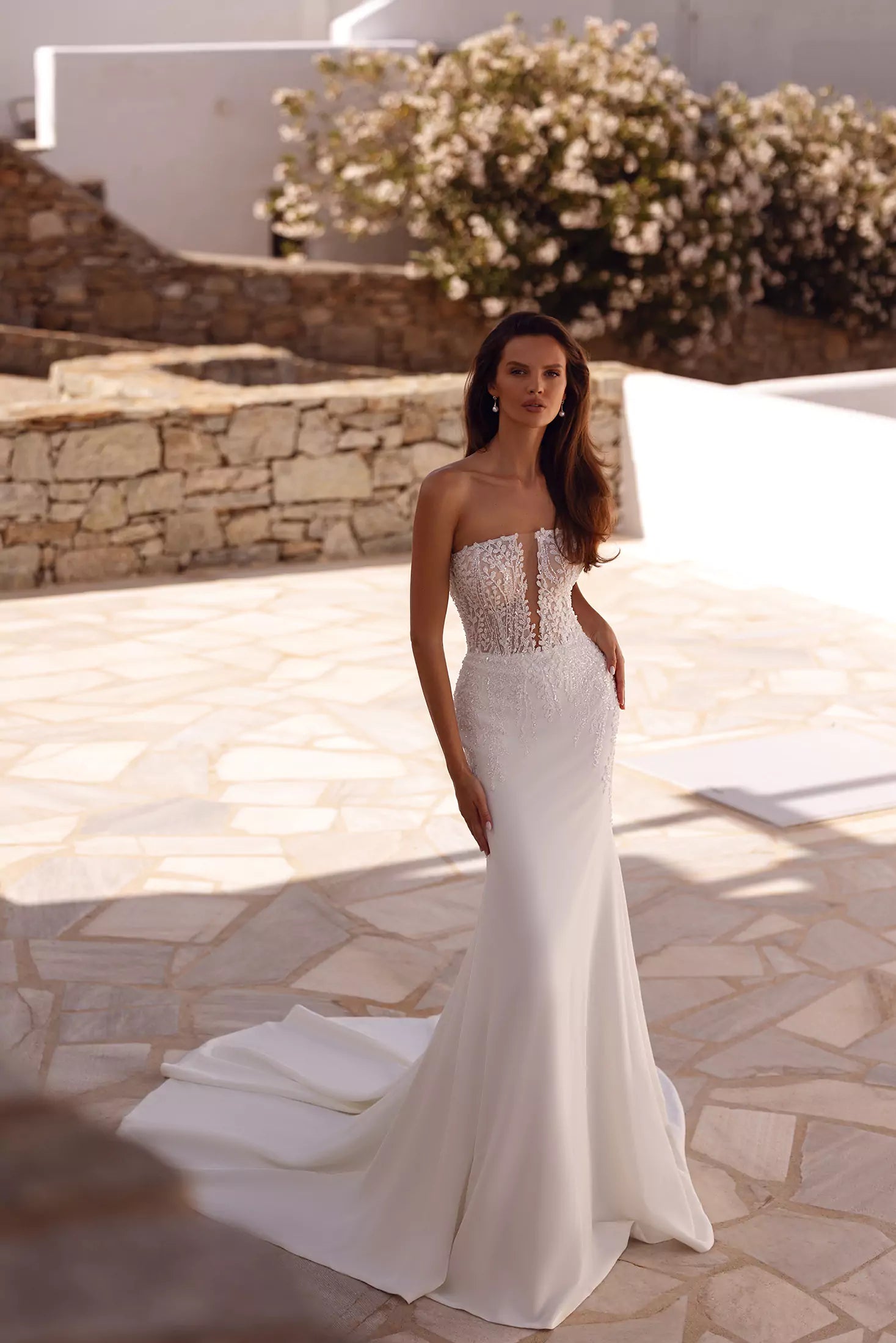 Strapless fitted wedding gown with sheer lace bodice and flowing train in Mediterranean setting — You&I Bridal | Endless UAE