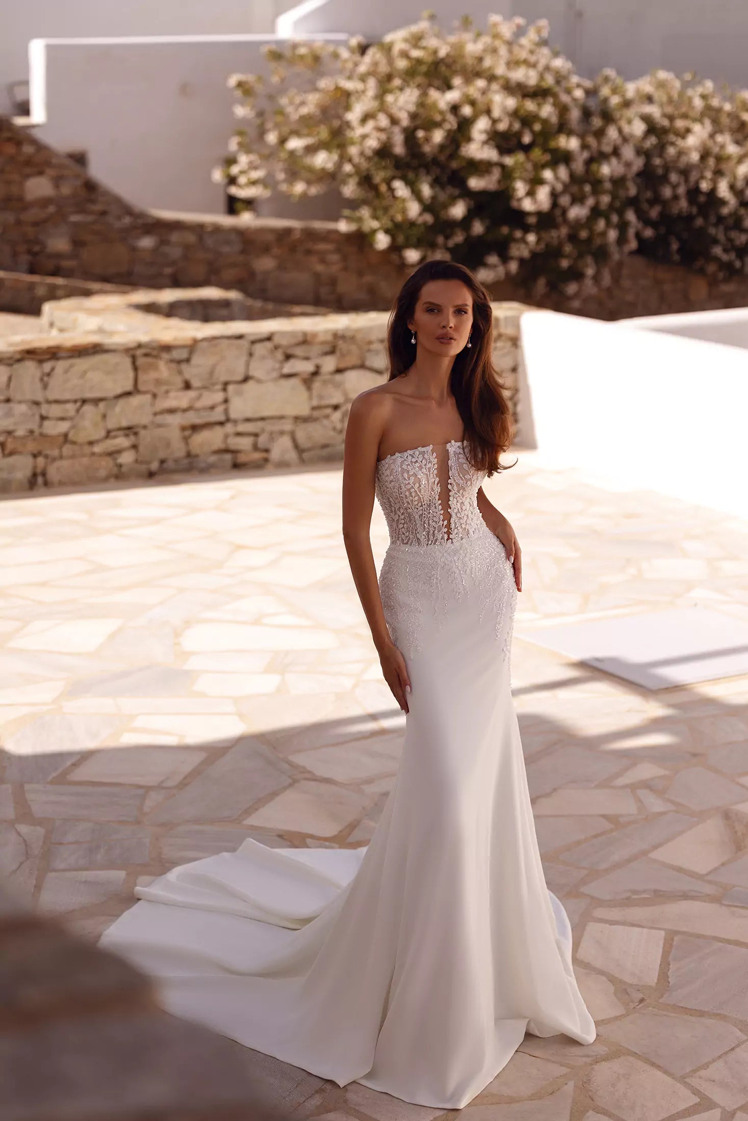 Strapless fitted wedding gown with sheer lace bodice and flowing train in Mediterranean setting — You&I Bridal | Endless UAE