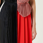 Woman wearing pleated asymmetric maxi dress in black, blush pink and red with black ankle strap heels — Victoria Beckham | Endless UAE
