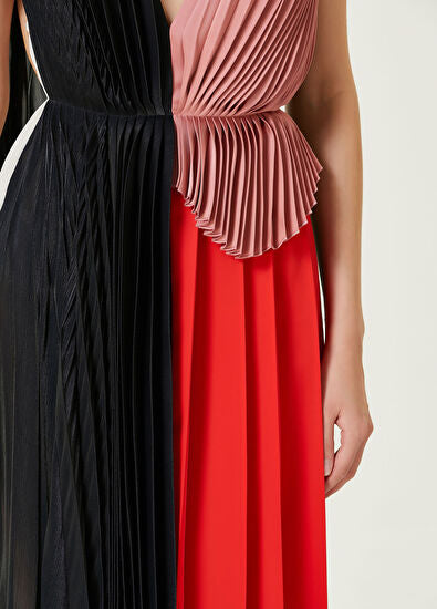Woman wearing pleated asymmetric maxi dress in black, blush pink and red with black ankle strap heels — Victoria Beckham | Endless UAE