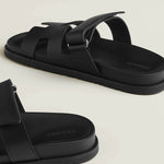 Black leather slide sandals with adjustable buckle straps and textured rubber sole — Hermes | Endless UAE