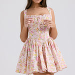 Pink floral print mini dress with gathered bodice, adjustable straps and full skirt modeled on brunette woman — House of CB | Endless UAE