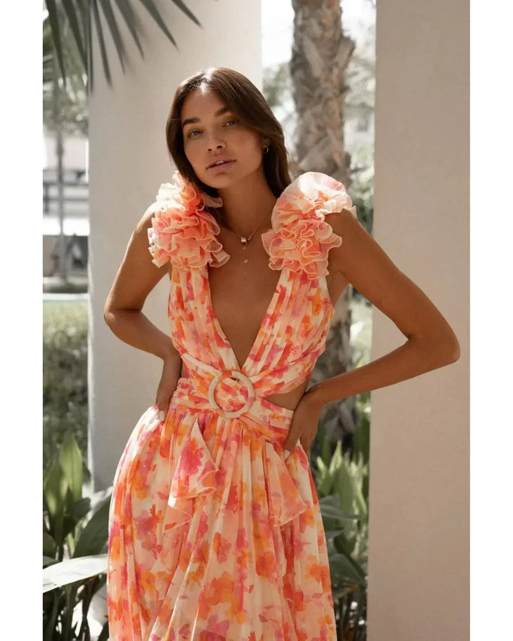 Woman wearing a coral floral maxi dress with flutter sleeves and cutout waist detail — Anne Louise Boutique | Endless UAE