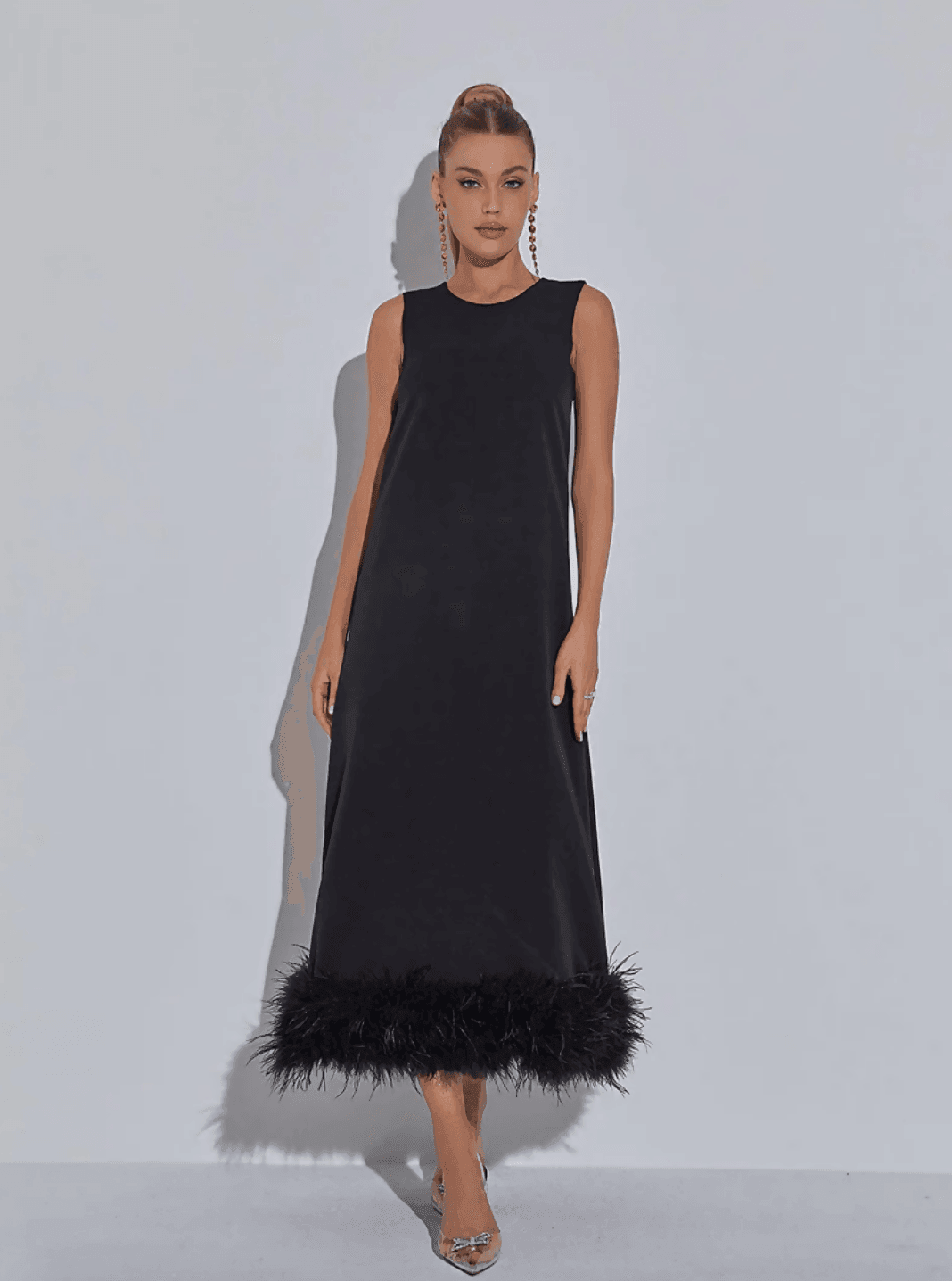 Black sleeveless midi dress with dramatic feather hem trim worn by model with slicked back hair and statement earrings — Mew Mews | Endless UAE