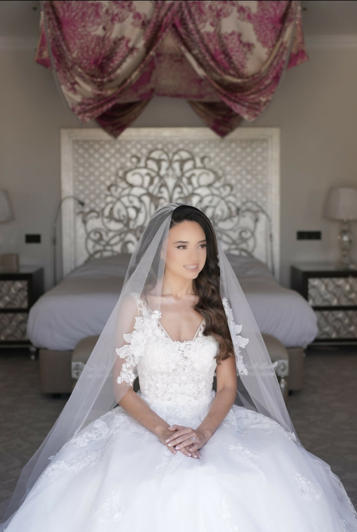 Bride wearing white lace ballgown wedding dress with illusion sleeves and cathedral veil in elegant bedroom — Rosa Clara | Endless UAE