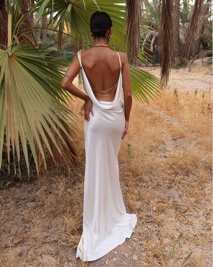 Woman wearing white cowl neck sleeveless maxi dress against textured beige wall — Rat & Boa | Endless UAE