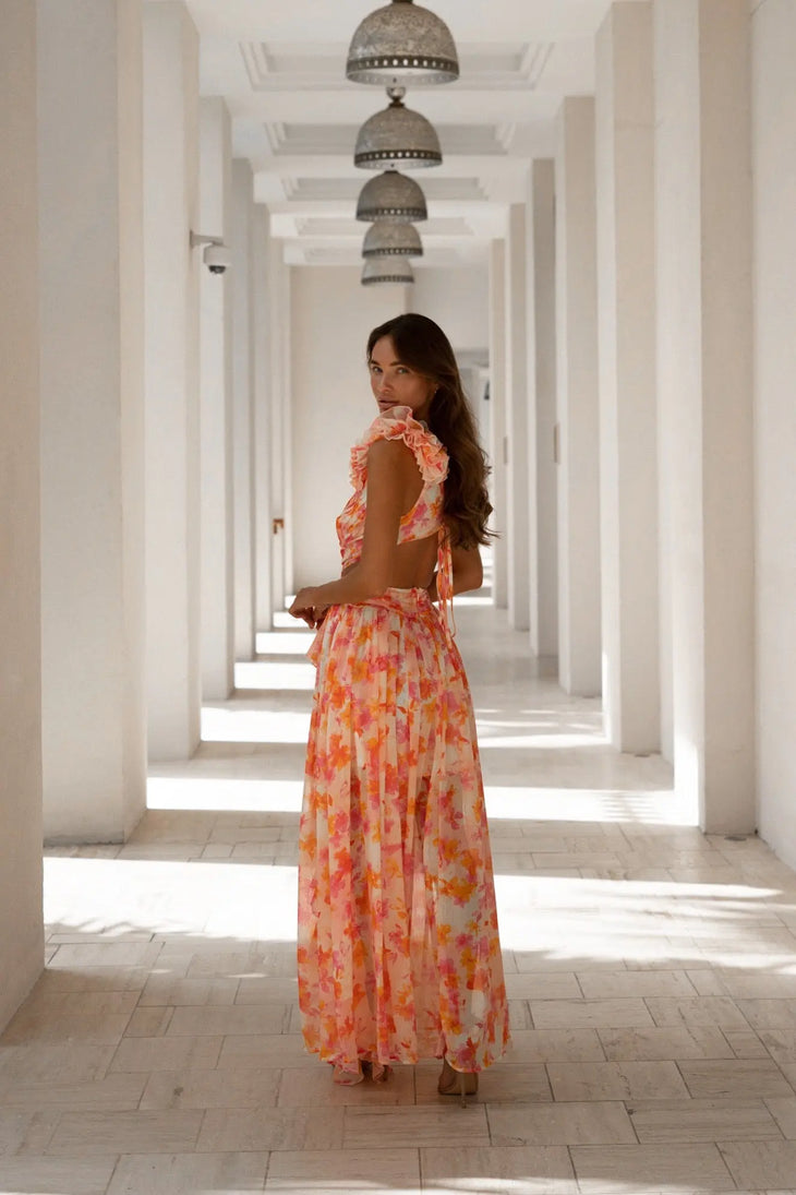 Woman in floral orange and fuchsia open-back maxi dress in white hallway — Anne Louis Boutique | Endless UAE