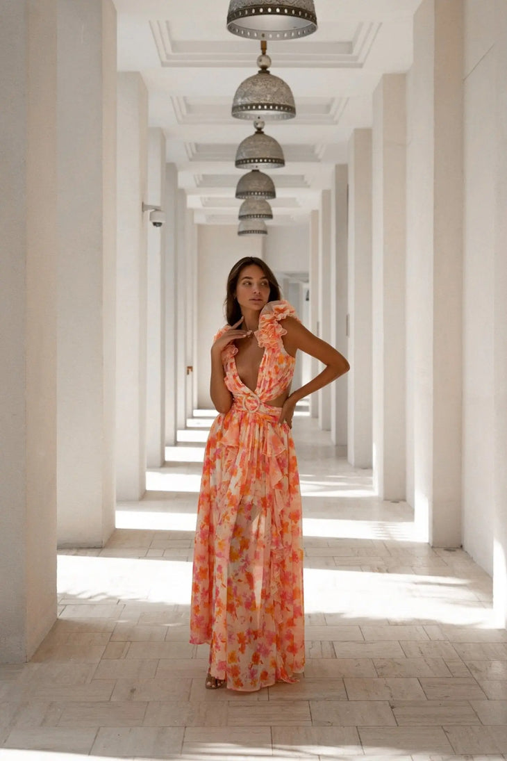 Woman in orange floral print maxi dress with ruffled neckline in white hallway — Anne Louis Boutique | Endless UAE