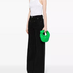 Bright green leather hobo bag held by model in white ribbed tank and black wide-leg pants — Bottega Veneta | Endless UAE