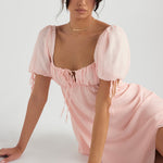 Pink puff sleeve mini dress with sweetheart neckline and tie front detail on model sitting — House of CB | Endless UAE
