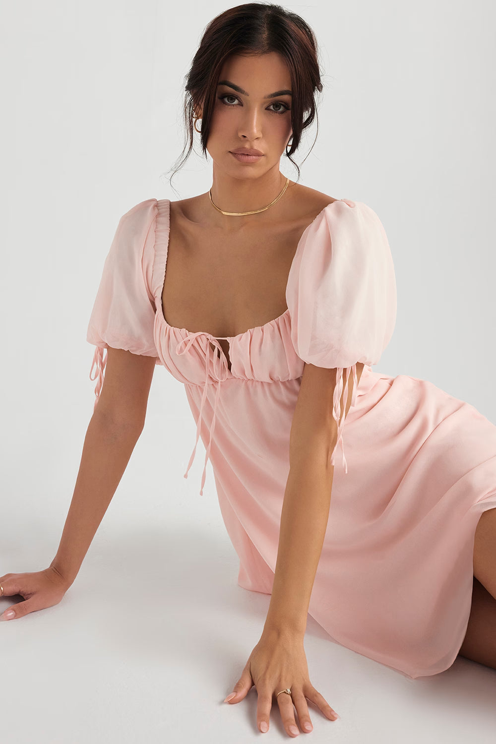 Pink puff sleeve mini dress with sweetheart neckline and tie front detail on model sitting — House of CB | Endless UAE