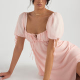 Pink puff sleeve mini dress with sweetheart neckline and tie front detail on model sitting — House of CB | Endless UAE