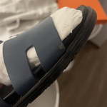 Black leather slide sandals with cutout straps displayed on orange box — Hermès | Endless UAE