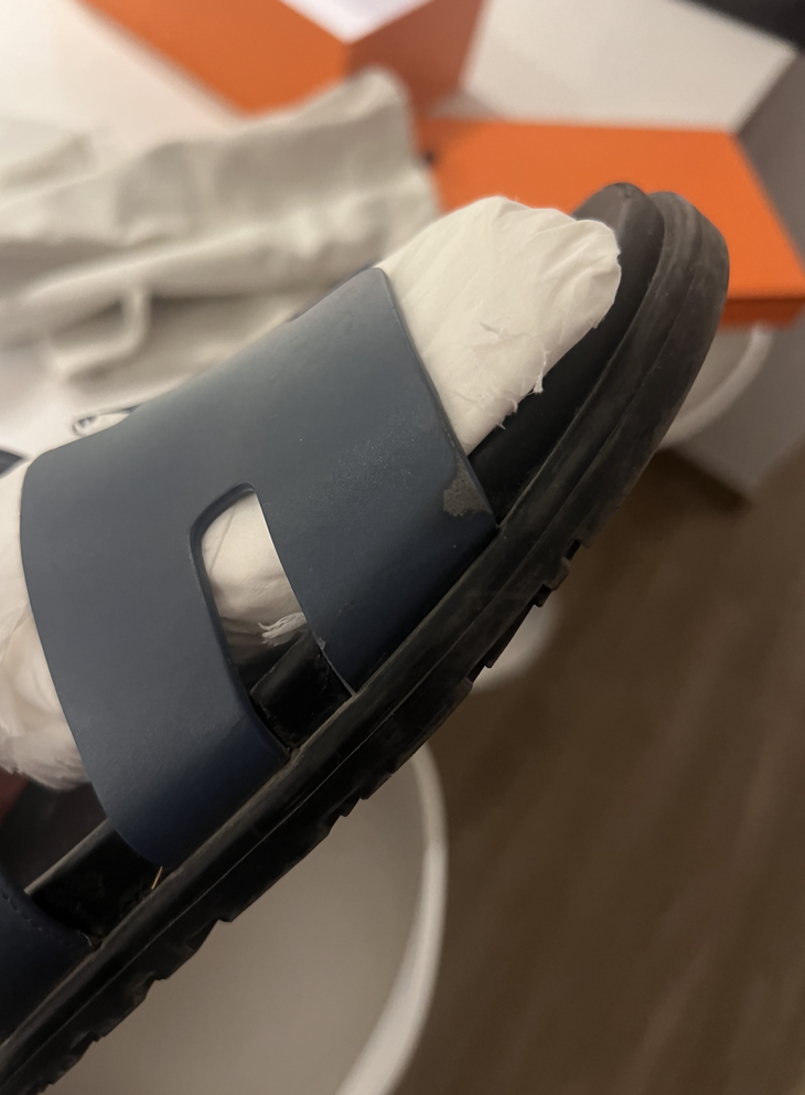 Black leather slide sandals with cutout straps displayed on orange box — Hermès | Endless UAE