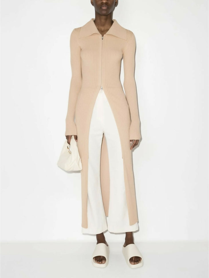 Beige ribbed knit midi dress with front zip closure and long sleeves worn with white pants and slides — Nanushka | Endless UAE
