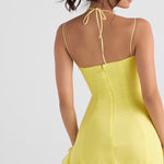 Rear view of woman wearing yellow mini dress with halter neck tie, spaghetti straps, and ruffle hem — House of CB | Endless UAE