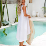 Woman wearing white sleeveless linen midi dress by pool holding straw hat — Magic Linen | Endless UAE